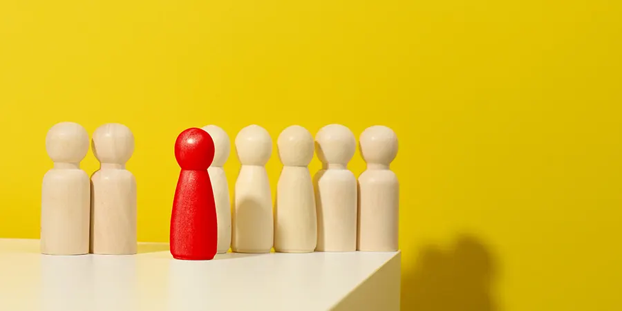 Should You Do a Roth Conversion Before Moving Abroad Blog Image 01 One red bowling pin standing out among beige pins on a white table against a yellow backdrop