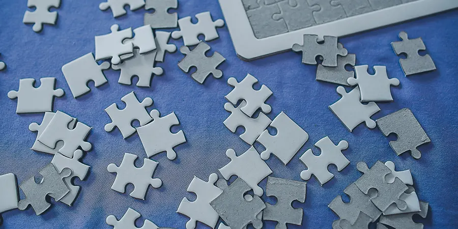 UK pension consolidation for Expats Blog Image Puzzle pieces on a blue background symbolising UK pension consolidation for expats and the challenge of combining retirement plans.