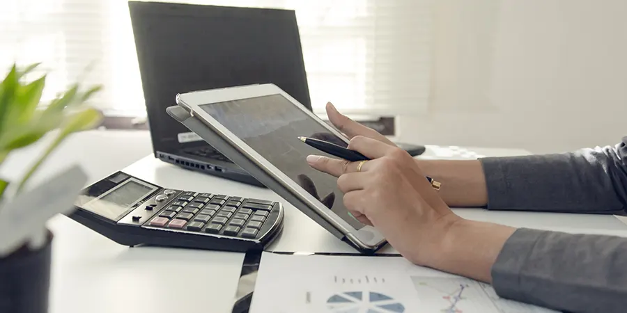 Managing Your Finances as an American Retiree Abroad Close-up of a person working on a tablet, reviewing financial planning documents for retirement abroad